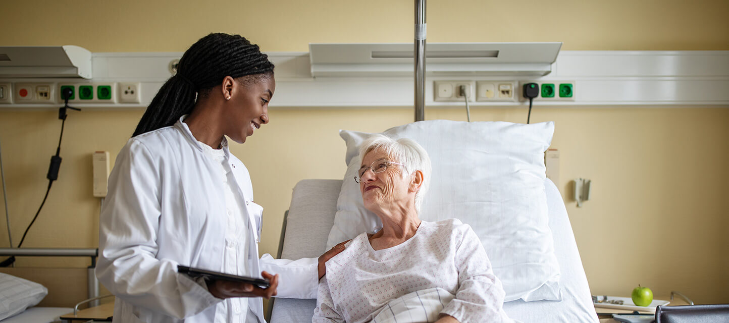 elderly patient in hospital bed speaking with female physician