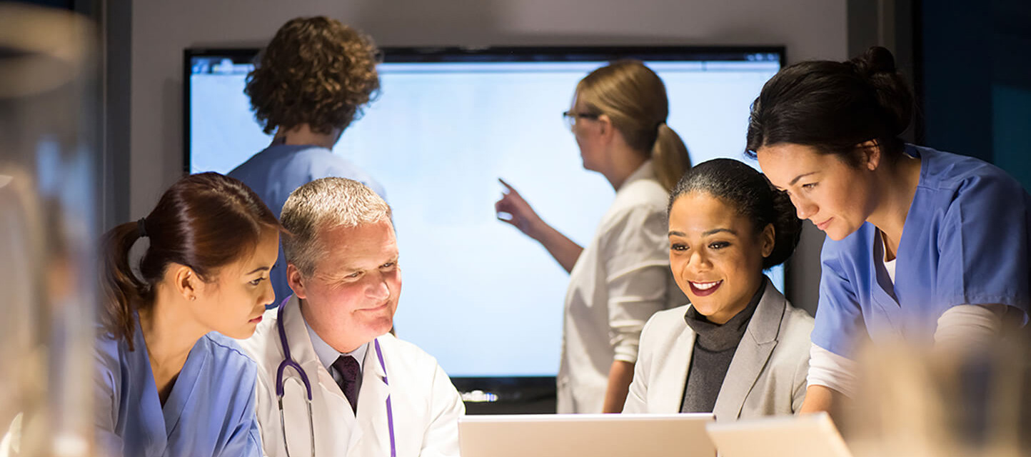 healthcare team looking at monitors and laptops in a meeting