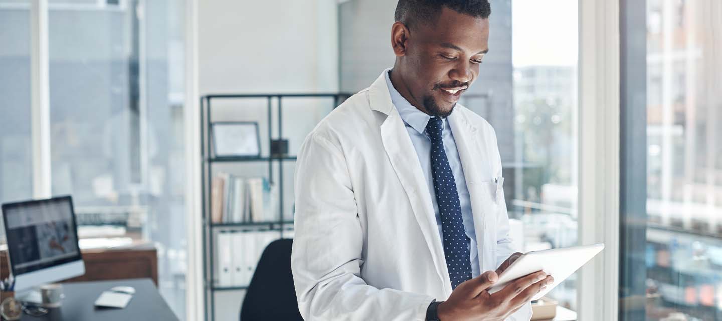 physician in his office looking at a mobile tablet