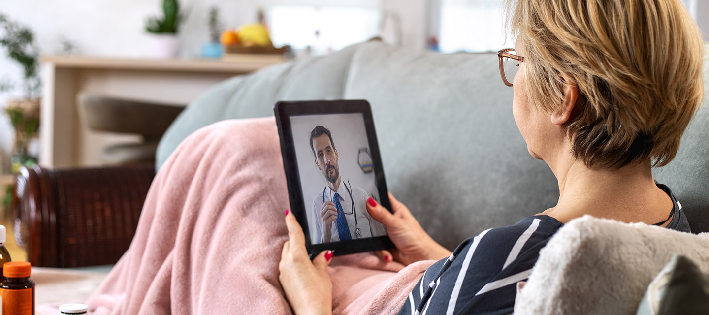 female patient on her couch using a mobile device to speak with her doctor