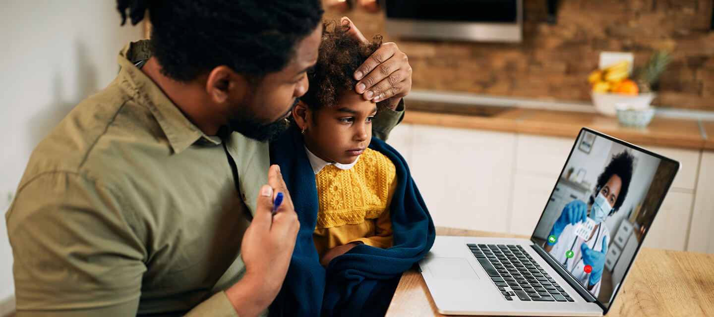 father with child talking to physician virtually through his laptop