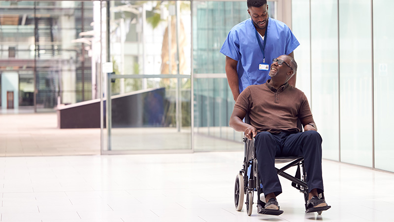 Male nurse assisting elderly in wheelchair