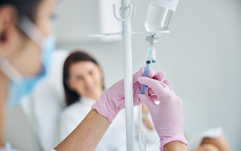 Nurse administering infusion into patient's IV bag