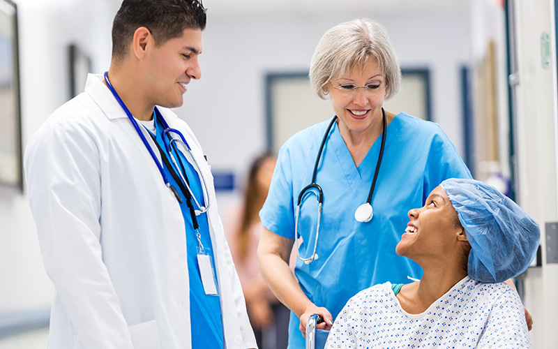 Nurse and doctor talking with happy patient