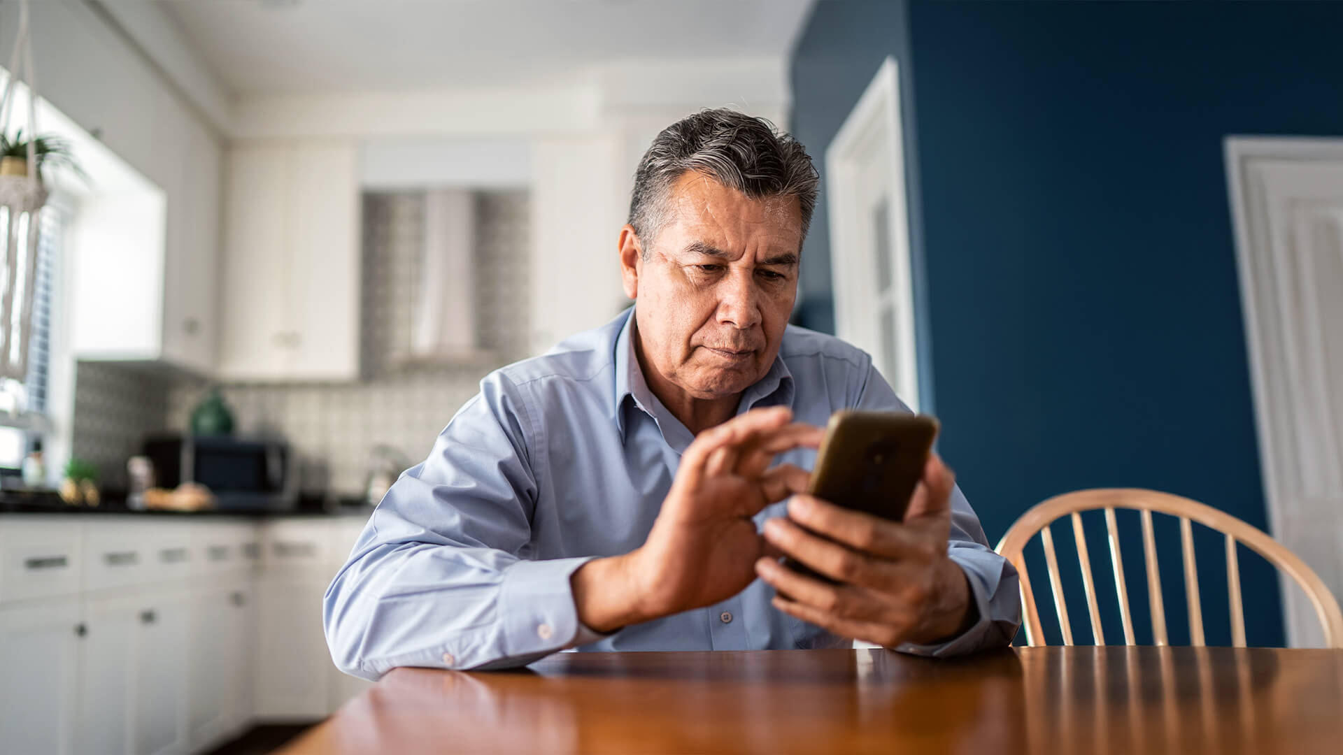 Older man using a smartphone at a table