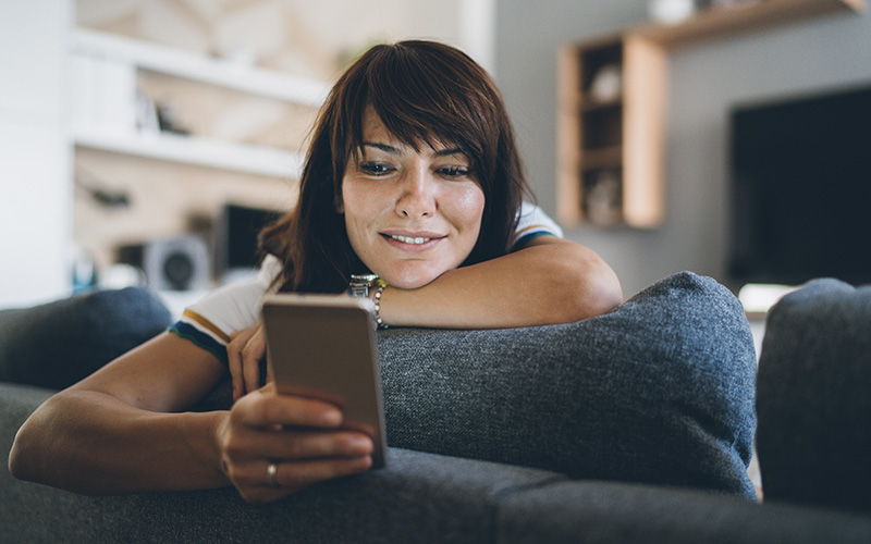 Woman looking at her phone while sitting on a couch
