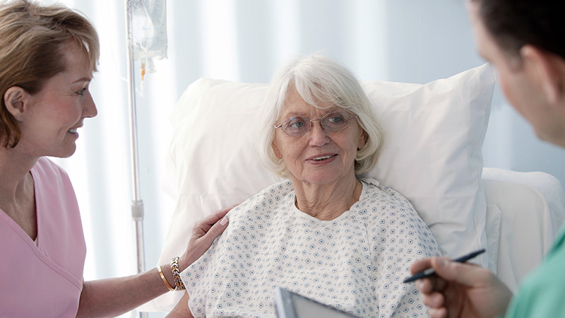 nurse and doctor visiting patient in hospital bed