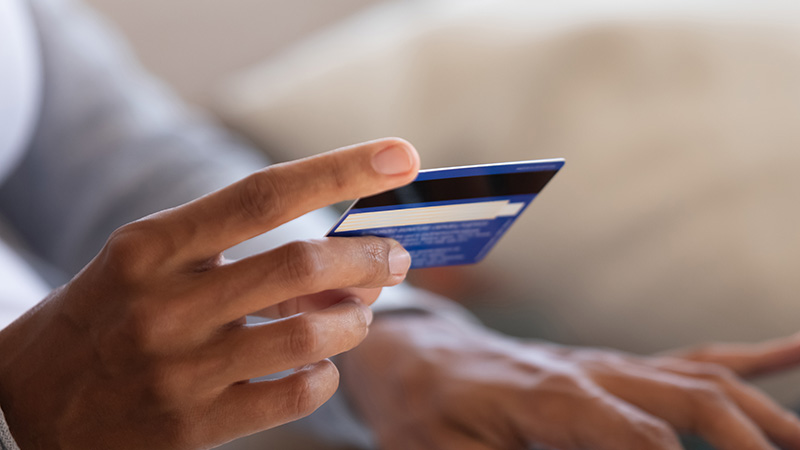 Holding bank card while typing on laptop