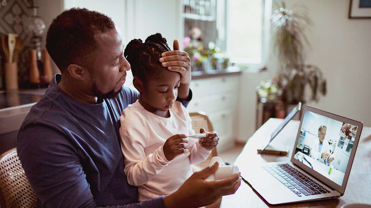 Father caring for his daughter and consulting a physician virtually