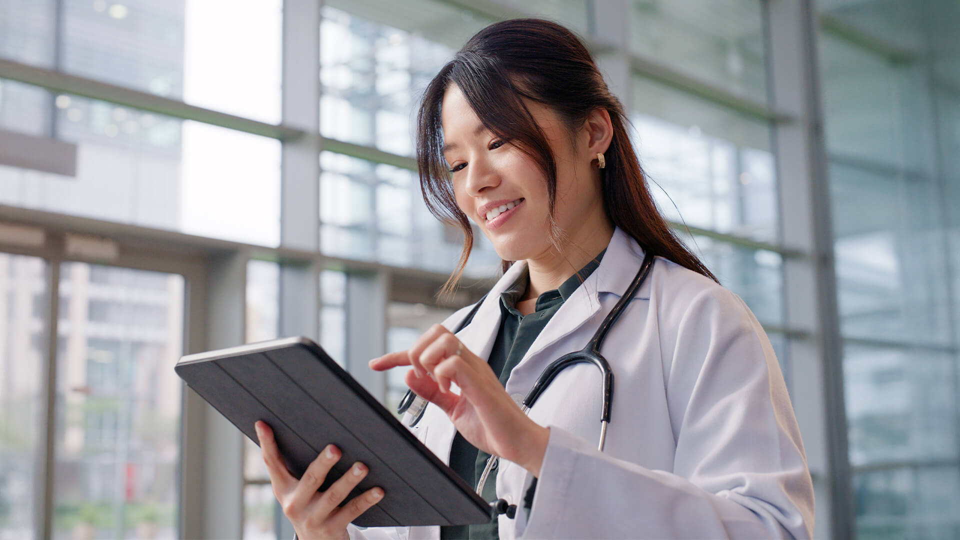 Female doctor using her digital tablet while standing in the consultation