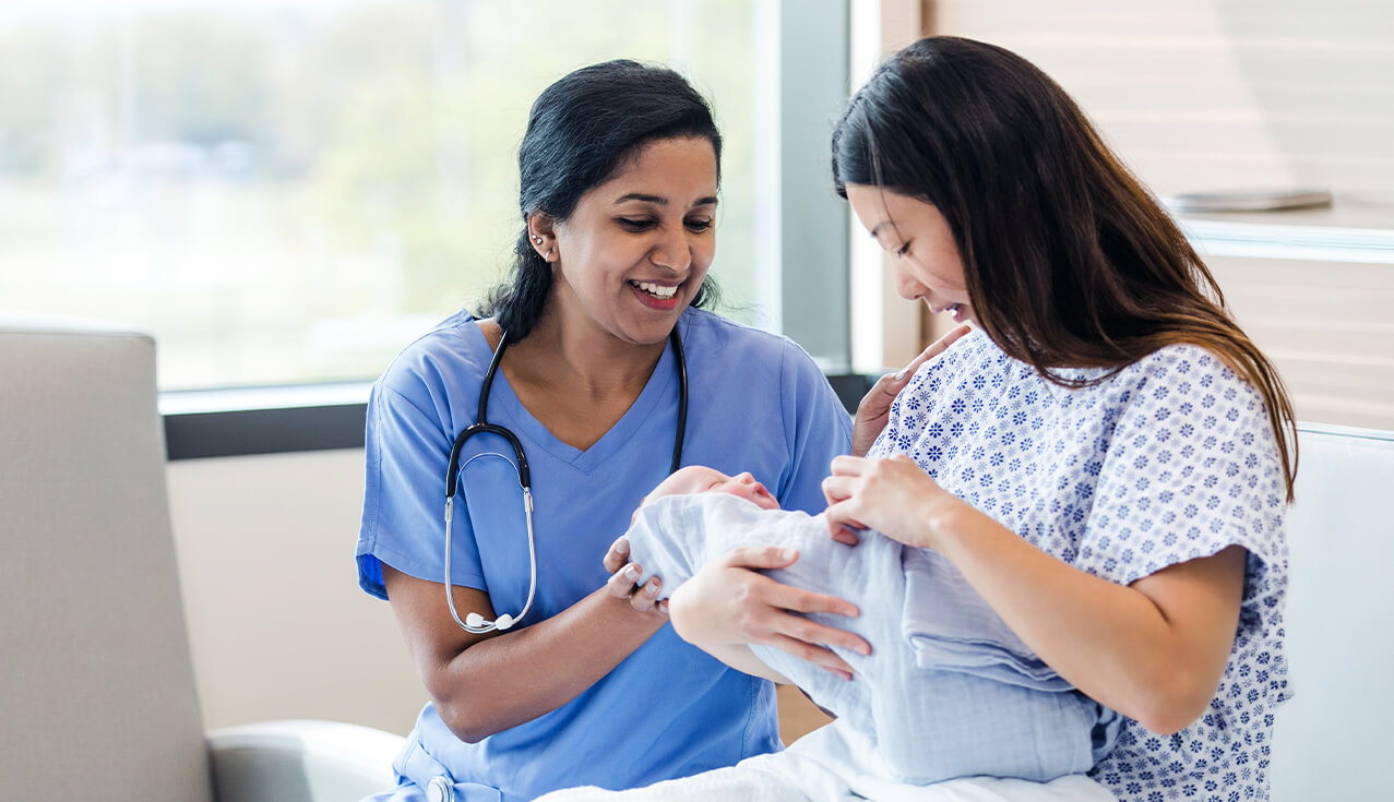 Mother holding newborn with nurse