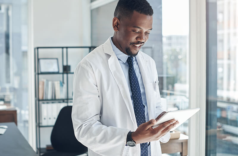 black doctor using tablet while standing in his office