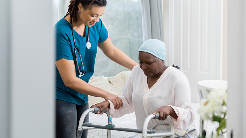 Care taker assisting hospice patient with walker