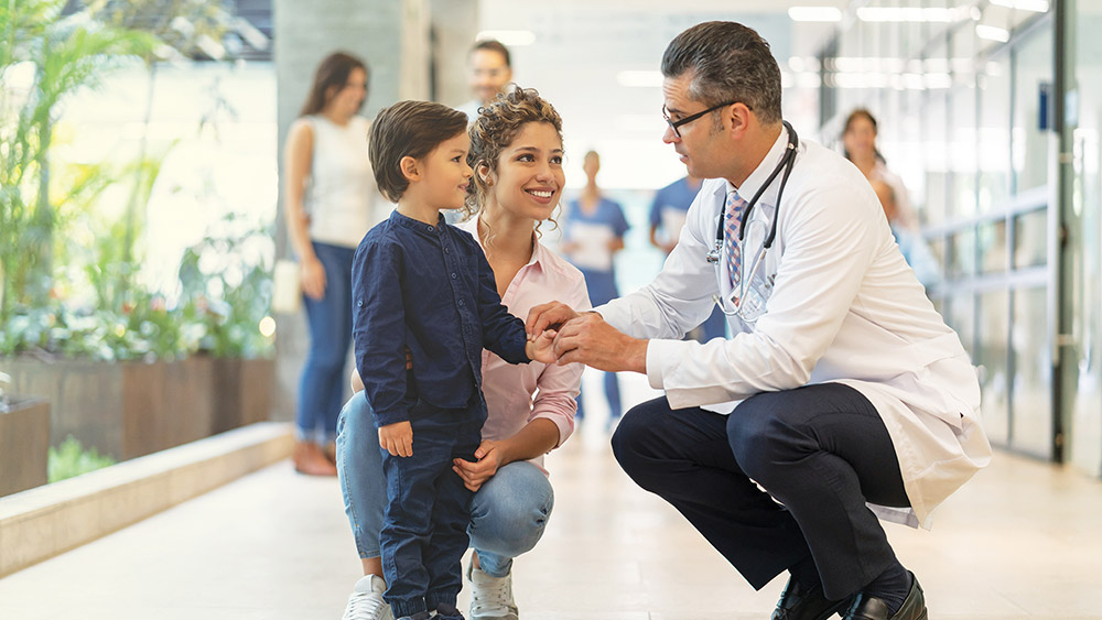 Physician examining small child with mother nearby