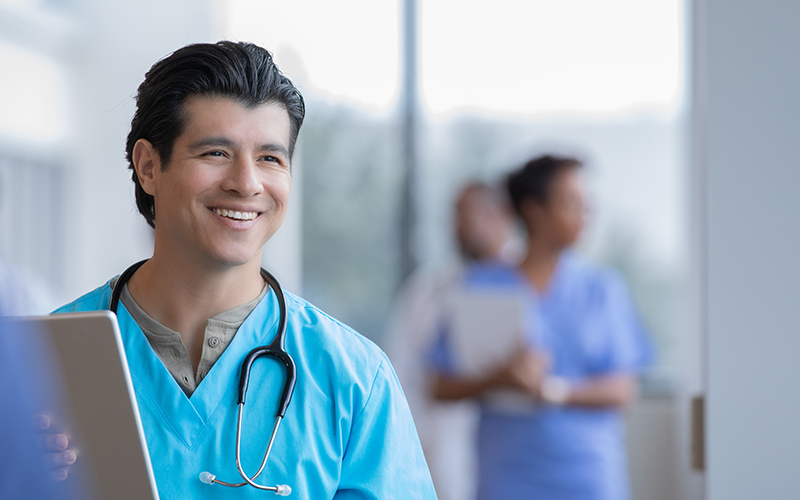 Hispanic male doctor holding a tablet and smiling