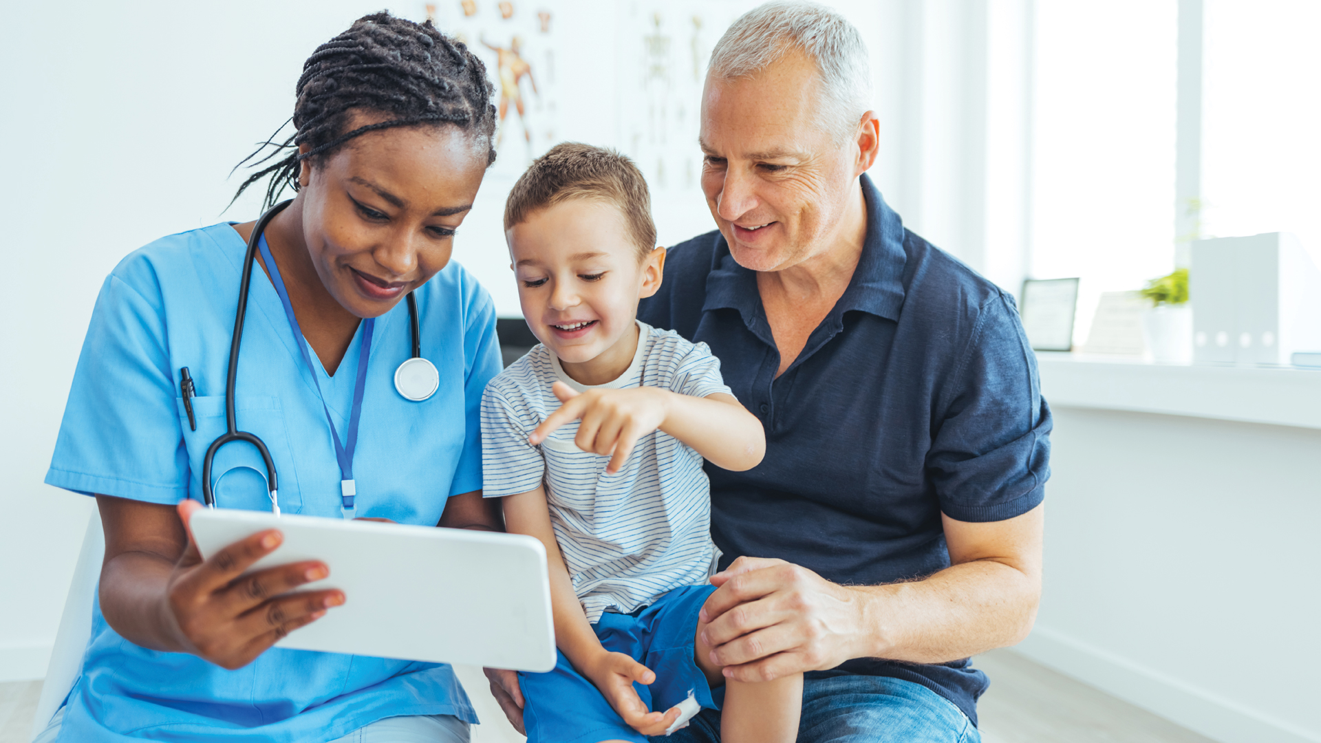 Doctor discussing care plan on tablet with young patient and father