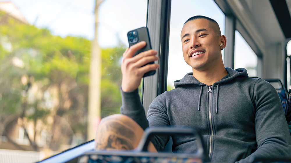 Asian male using his phone while on a train