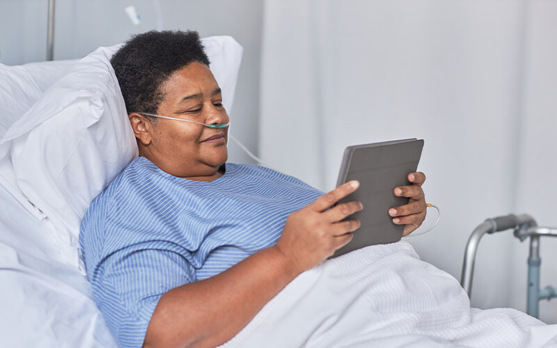 patient with tablet in hospital bed