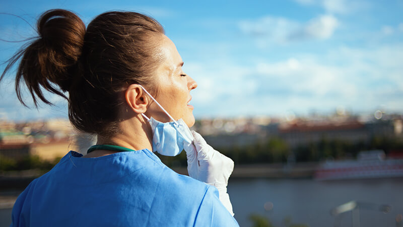 Relieved nurse removes mask outside and takes a deep breath